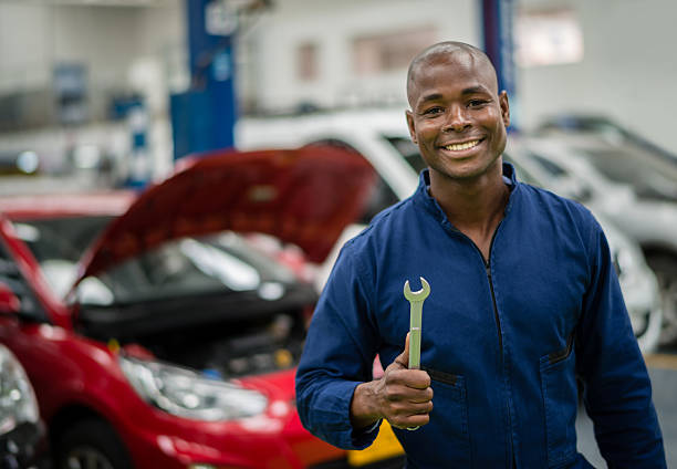 happy mechanic holding tools at a car garage